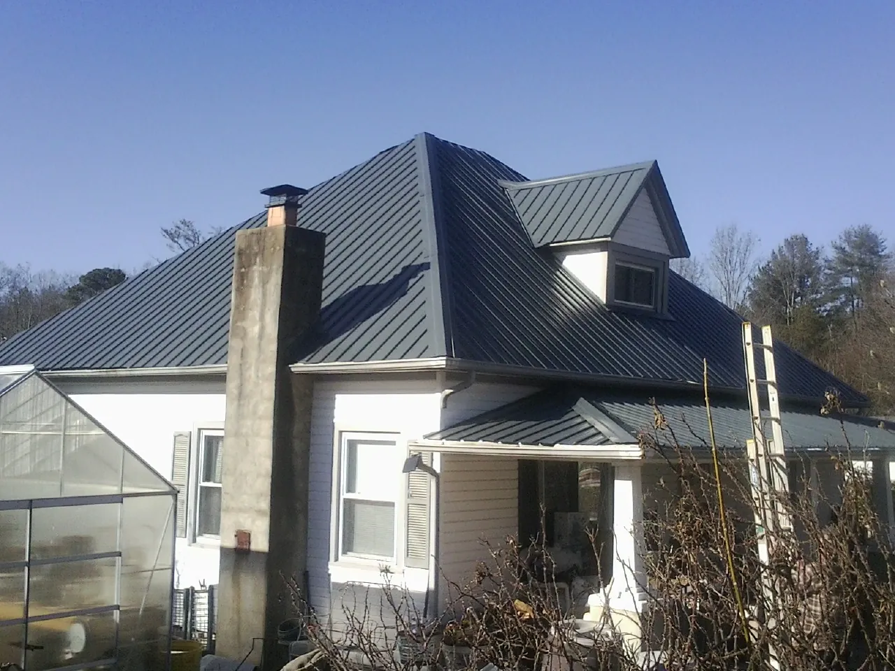 Dark blue standing seam metal roof on a white farmhouse with dormer — Slate & Tile Roof Repair by Roofing Brothers in Fishtail