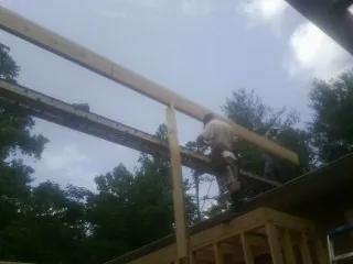 Carpenter setting a ridge beam over a new addition frame — Ice Dam Removal by Roofing Brothers in Fishtail