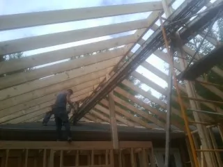 Rafters going up over a new addition with a worker on the wall in Fishtail