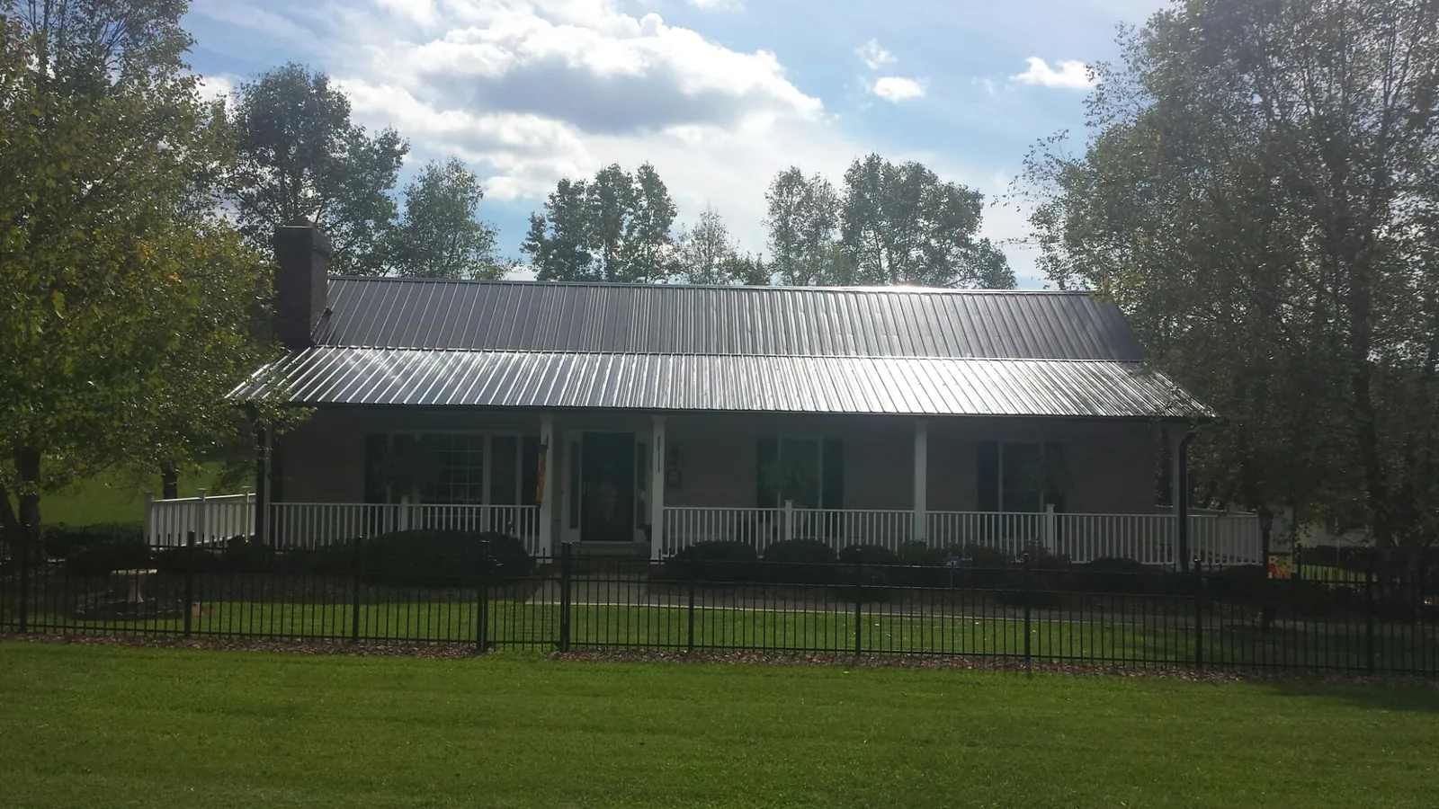 Gray metal roof on a brick ranch with a full width front porch — Gutter Guard Installation work by our crew in Fishtail