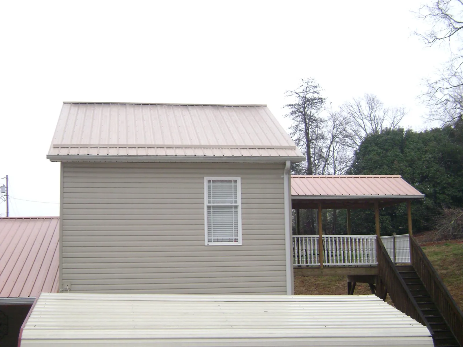 Tan metal roofs on a two story addition and attached porch, from a Roof Replacement job in Fishtail