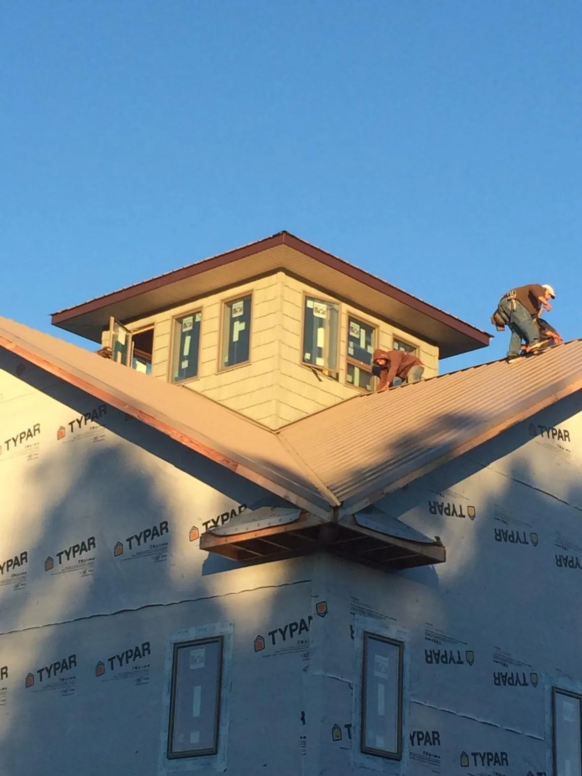 Roofers working around a rooftop cupola on a new metal roof at sunset — Roof Waterproofing in Fishtail by Roofing Brothers